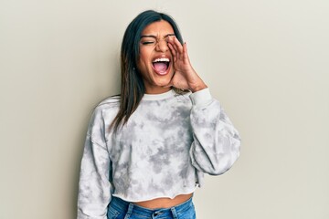 Young latin transsexual transgender woman wearing casual clothes shouting and screaming loud to side with hand on mouth. communication concept.