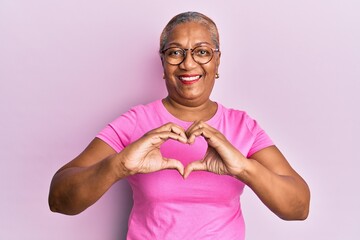 Senior african american woman wearing casual clothes and glasses smiling in love showing heart symbol and shape with hands. romantic concept.
