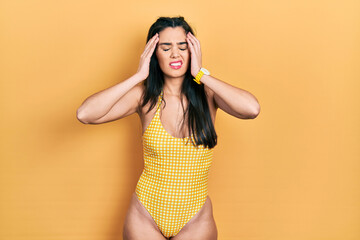 Young hispanic girl wearing swimsuit with hand on head, headache because stress. suffering migraine.