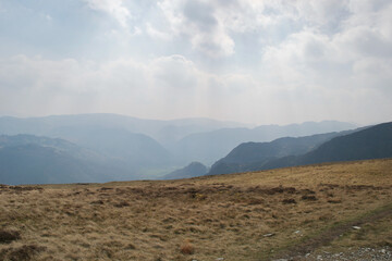 Sunbeams shimmering through the hazy sky; sunlight filtered through mist over layered distant mountains above valleys