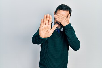 Middle age hispanic man wearing casual clothes and glasses covering eyes with hands and doing stop gesture with sad and fear expression. embarrassed and negative concept.