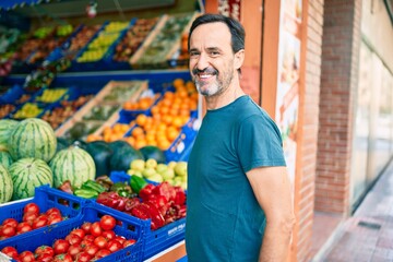 Middle age man with beard smiling happy shopping vegetables at the grocery supermarket