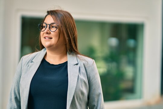 Young hispanic plus size businesswoman smiling happy standing at the city.