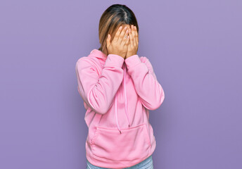 Young caucasian woman wearing casual sweatshirt with sad expression covering face with hands while crying. depression concept.