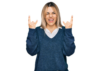 Young caucasian woman wearing casual clothes shouting with crazy expression doing rock symbol with hands up. music star. heavy music concept.