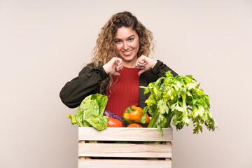 Farmer with freshly picked vegetables in a box isolated on beige background proud and self-satisfied