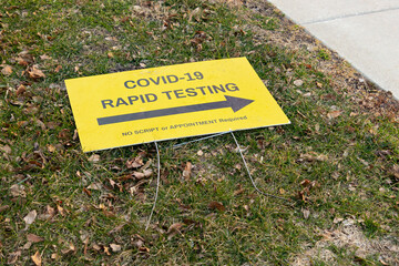 COVID-19 rapid testing site sign laying on the ground, signifying the end of the pandemic