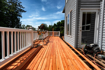 Complete home outdoor deck remodel with new red cedar wooden boards being installed - 423316103