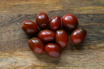 cherry tomatoes dark red burgundy sprinkled on a wooden background