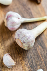 pair of garlic head in the center of scattered cloves on a wooden background