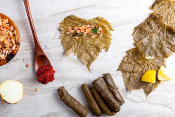 Yaprak sarmasi is a traditional Turkish dish made by wrapping rice stuffing with grape leaves. Flat lay image showing the ingredients during preparation of the sarma dish.