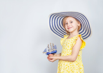 A girl in a wide-brimmed hat holds a toy boat in her hands.