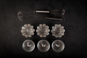 kitchen utensils on dark background, seen from above.