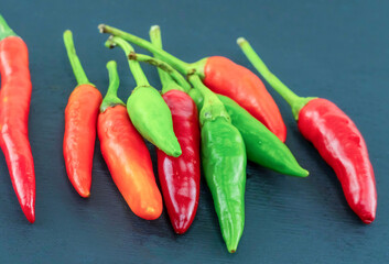 hot green and red chili peppers lie on a black background, small pods the base of shirachi sauce