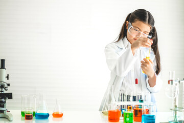 Cute little girl student child learning research and doing a chemical experiment while making analyzing and mixing liquid in glass at science class in school.Education and science concept