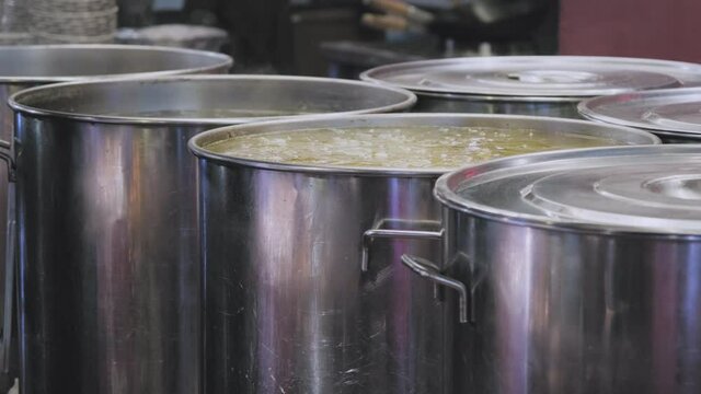 In the huge cauldrons of the Oriental restaurant, the broth for ramen boils. A woman hand scoops up the soup with a ladle and pours it into a bowl