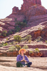 Woman in hat on rocks meditating