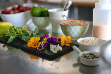 ingrédients et fleurs déposés sur un comptoir en acier inoxydable dans une cuisine