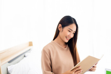 Naklejka premium Beautiful asian woman reading book on bed,Happy and smiling,Relax time