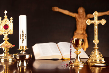 Religious holiday – Easter. Catholic symbols composition. Jesus figure, The Cross, monstrance,  Holy Bible, rosary and golden chalice on gray background. 