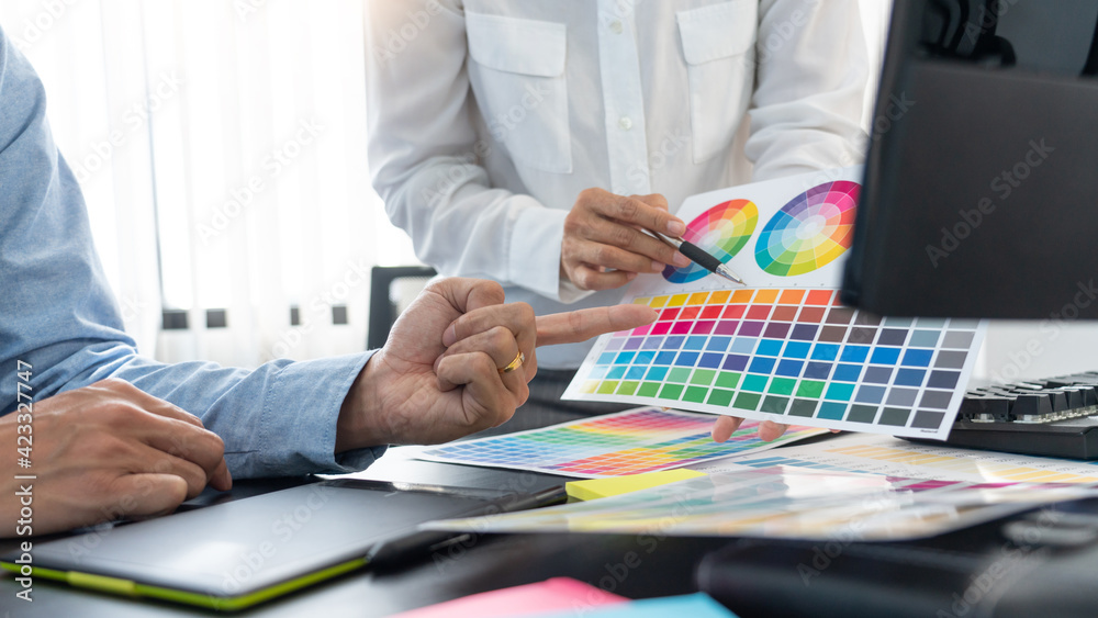 Poster graphic designer team working on web design using color swatches editing artwork using tablet and a 