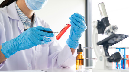 Young Asian scientist Working looking through a microscope doing research for analyzing a Experiments sample in a forensic laboratory.