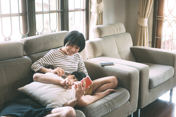 Young adult asian lover couple sitting on sofa cozy style indoor on day.