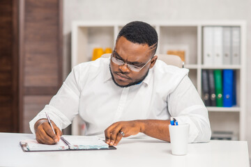 Freelance designer workplace at home office. Young African-American man works using a computer, graphics tablet and other devices. Remote job.