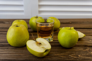 Green apples and glass with apple juice on wooden background