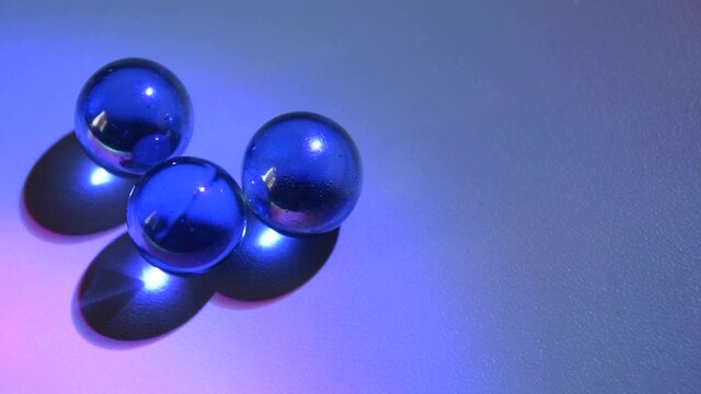 Moving glass marbles on white table children's game and moment of relaxation, multicolored light. 