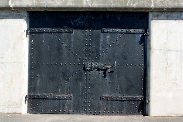 Old iron door reinforced with steel belts and rivets guarding the entrance to an old military fort.