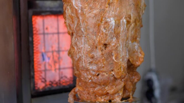 Meat is preparing on the spit. Turkish traditional cousin. Meat on vertical grill at a kebab shop.