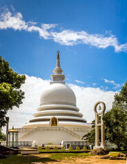 A religious building in Sri Lanka against the background of leafy trees and a blue sky with white clouds