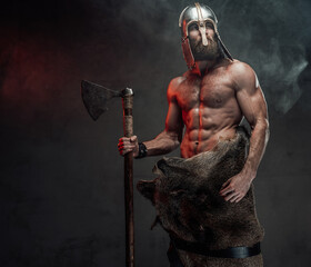 Naked nord warrior posing in dark background with axe