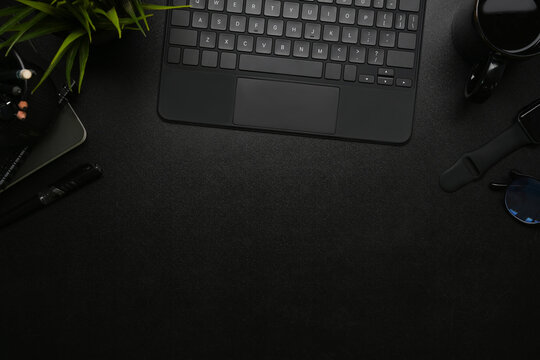 Top view of modern dark office with wireless keyboard, smart watch coffee cup on on black leather.