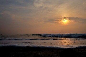 Obraz premium In selective focus silhouette sunrise with golden light on water surface and clean waves
