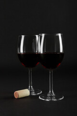 Two glass glasses of red wine on a black homogeneous background