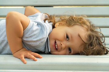 Portrait of a cheerful child lying on a bench