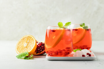Summer mocktail, orange slises pomegranate seeds citrus drink in glasses. Space for text.