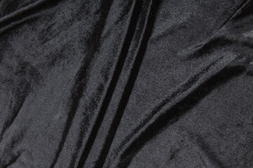 Colored black textile satin fabric folded in folds and waves with highlights and texture