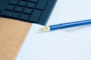 Planning, computer keyboard, notebook, and blue pen