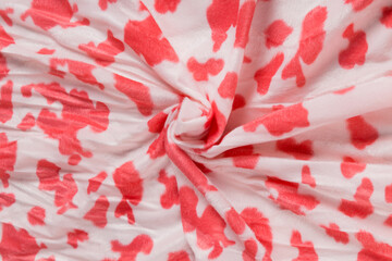 Colored red textile satin fabric folded in folds and waves with highlights and texture