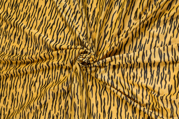 Colored yellow textile satin fabric folded in folds and waves with highlights and texture