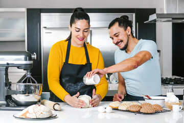 latin couple bakers preparing dough for baking mexican bread called Conchas in kitchen in Mexico city