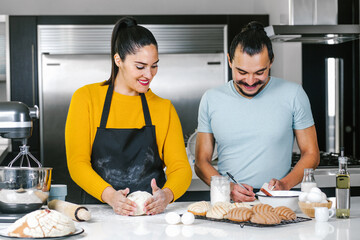 latin couple bakers preparing dough for baking mexican bread called Conchas in kitchen in Mexico city