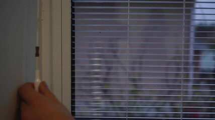 a man opens the blinds in the bathroom in the morning