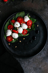 caprese salad on black plate on black background