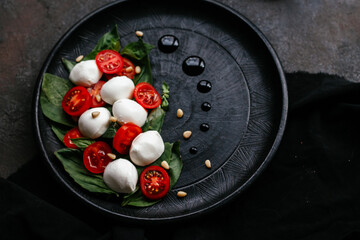caprese salad on black plate on black background