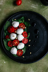 caprese salad on a black plate on a green background