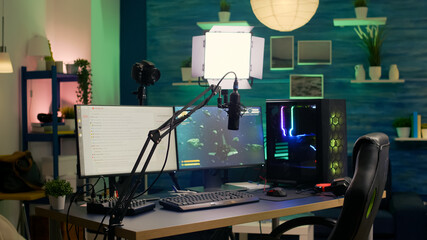 Empty streaming room with professional powerful computer, RGB keyboard and mouse, headphones and mirophone. Player talking with other players on streaming chat during online competition